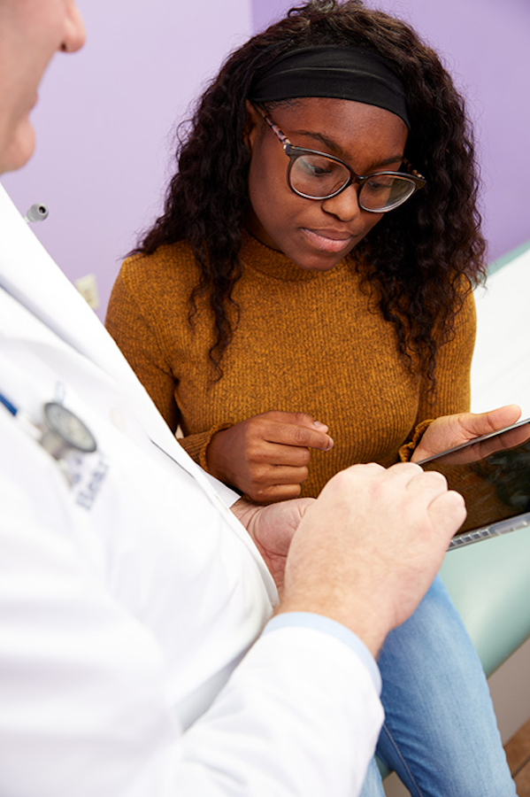 A young African American woman looking at a paper with a male doctor.