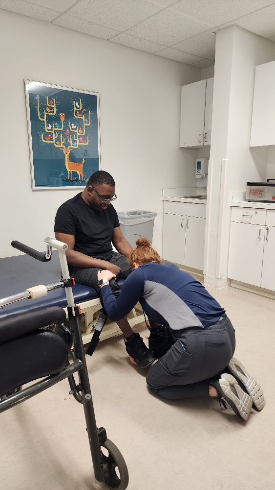 An African American man looking at a female therapist who is touching his leg.