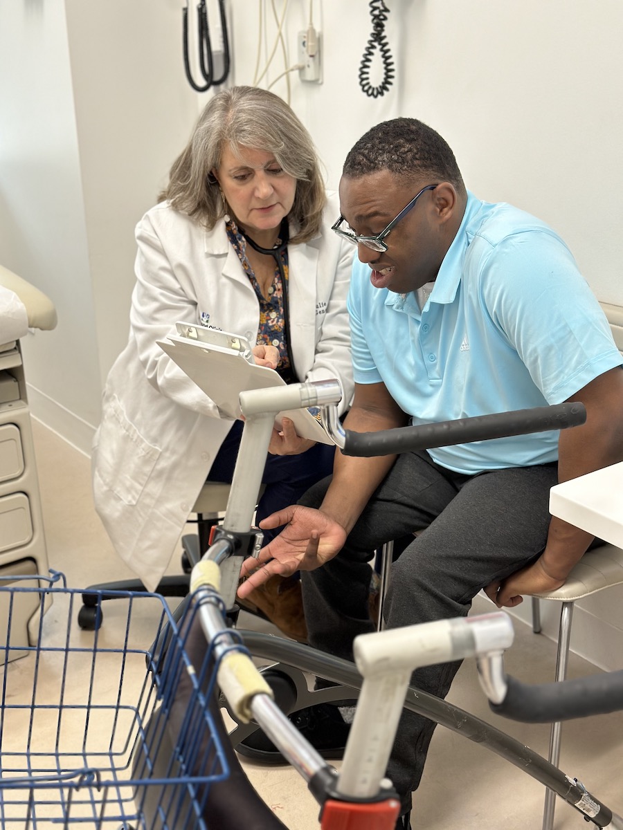 A young African American man looking at a paper with a White female doctor.