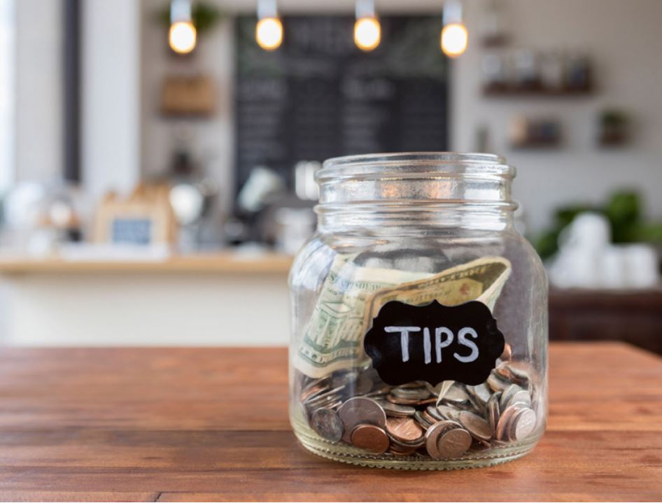 Money in a tip jar sitting on a table in a restaurant