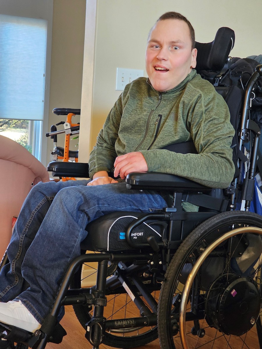 A white man sitting in a wheelchair and smiling at the camera