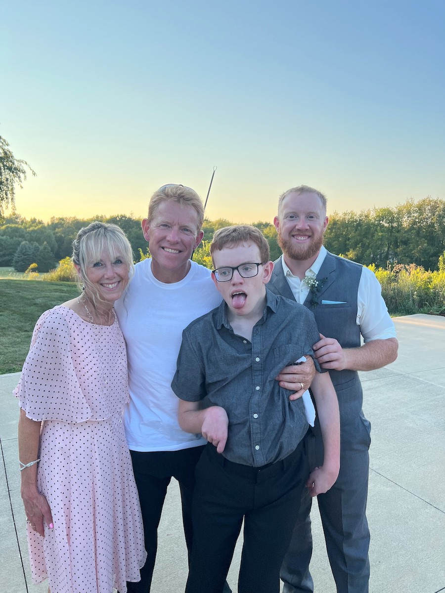 A White woman and three men standing together outside smiling.