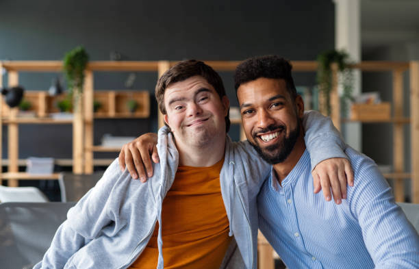 A happy, young White man with his arm around a happy, young African American man, smiling.