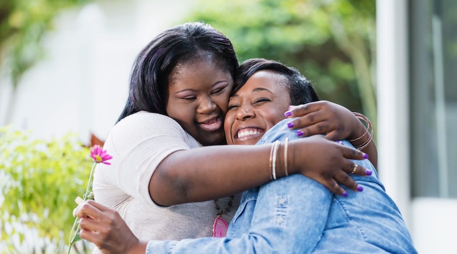 Two African American women hugging and smiling.